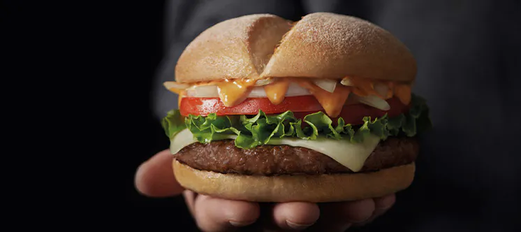 Un hombre con traje sujetando una hamburguesas