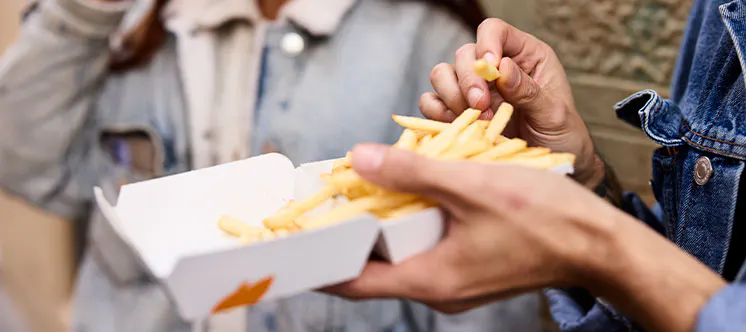 Dos personas disfrutando de unas patatas de McDonalds